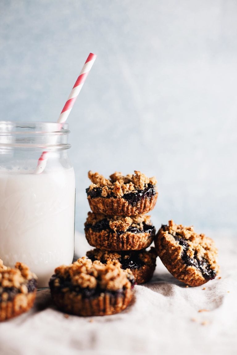 Miniature fruit pies stacked on top of each other next to a jar of milk