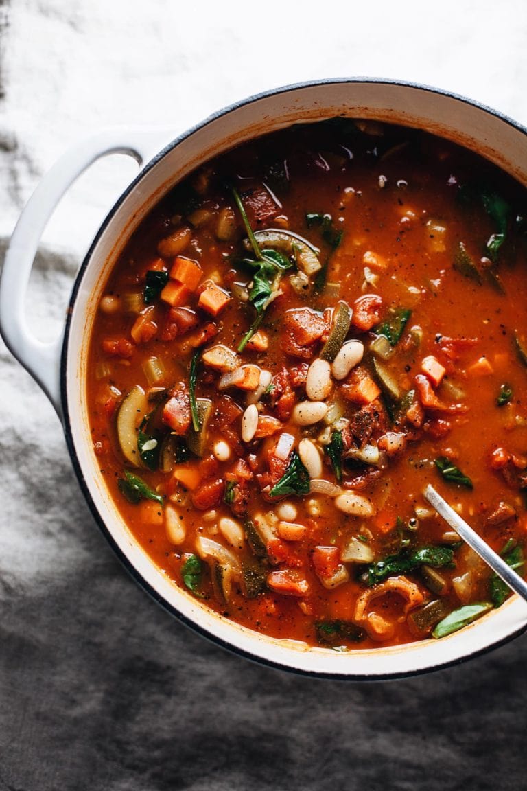 kale and white bean soup in cast iron pot on marble countertop
