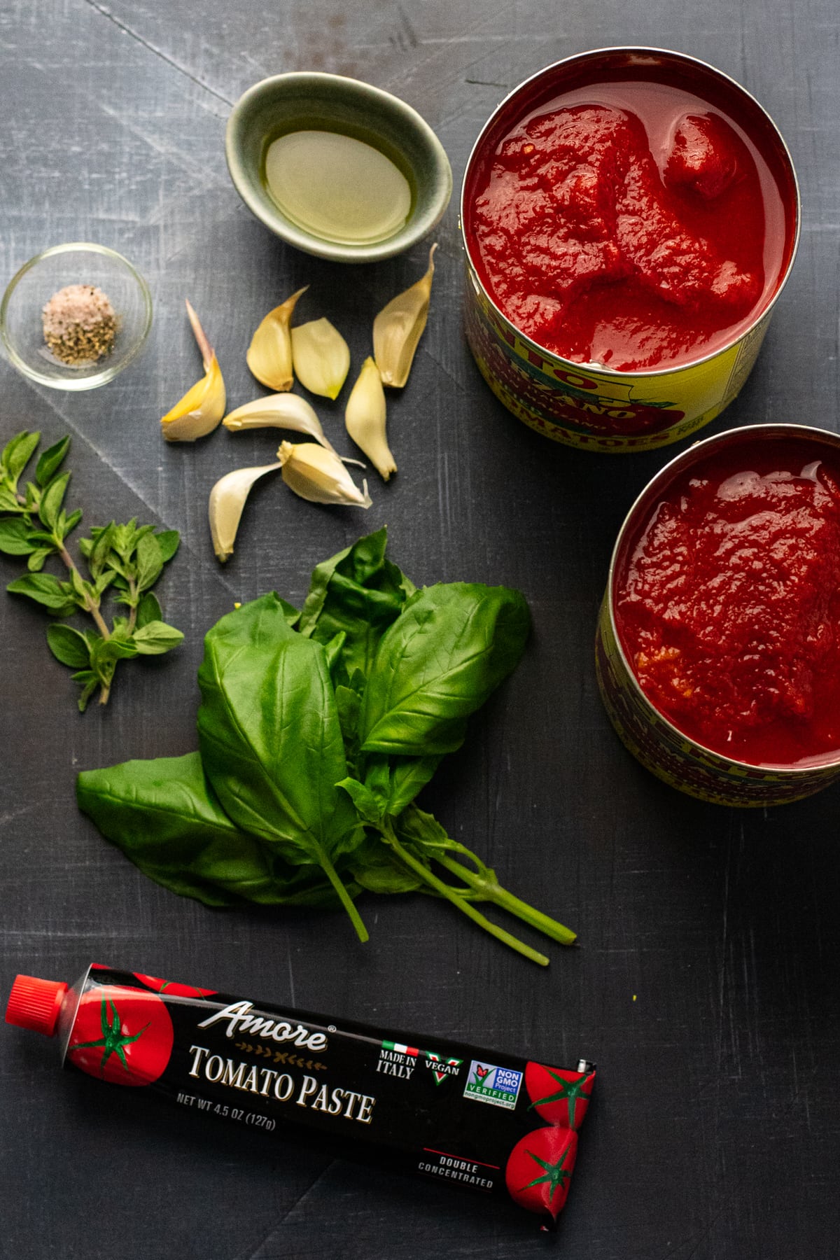 ingredients for tomato sauce arranged on gray background.