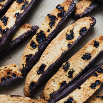 Italian biscotti dipped in dark chocolate laid on parchment paper.