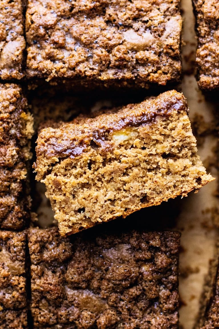 A close up of a slice of banana coffee cake with coffee cake in the background.