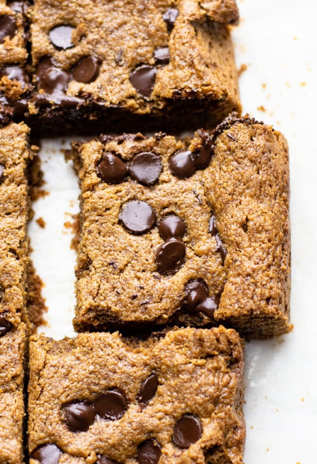 A close up image of chocolate chip oatmeal bar on white parchment paper.