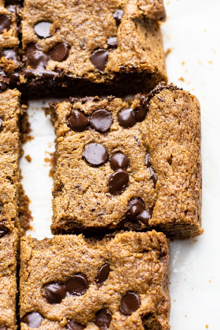 A close up image of chocolate chip oatmeal bar on white parchment paper.