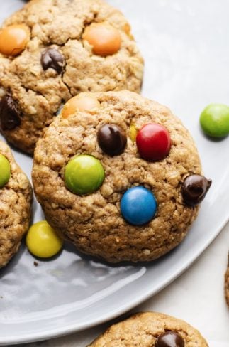a close up of a m&m and chocolate chip cookie on a grey plate.