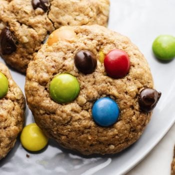 a close up of a m&m and chocolate chip cookie on a grey plate.
