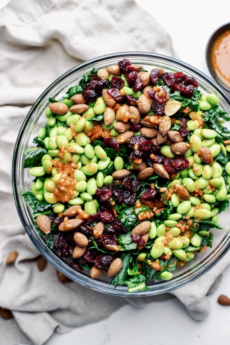 A clear glass bowl on a grey napkin with salad in it.