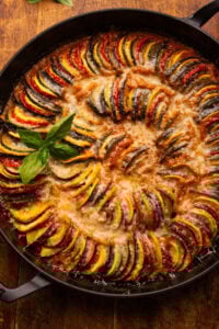 Ratatouille displayed in a cast iron braiser pan on a wooden board.