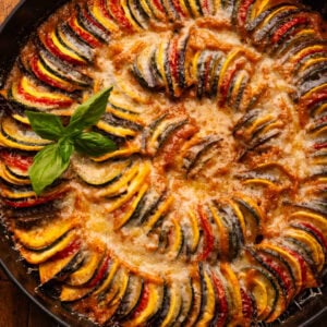 Ratatouille displayed in a cast iron braiser pan on a wooden board.