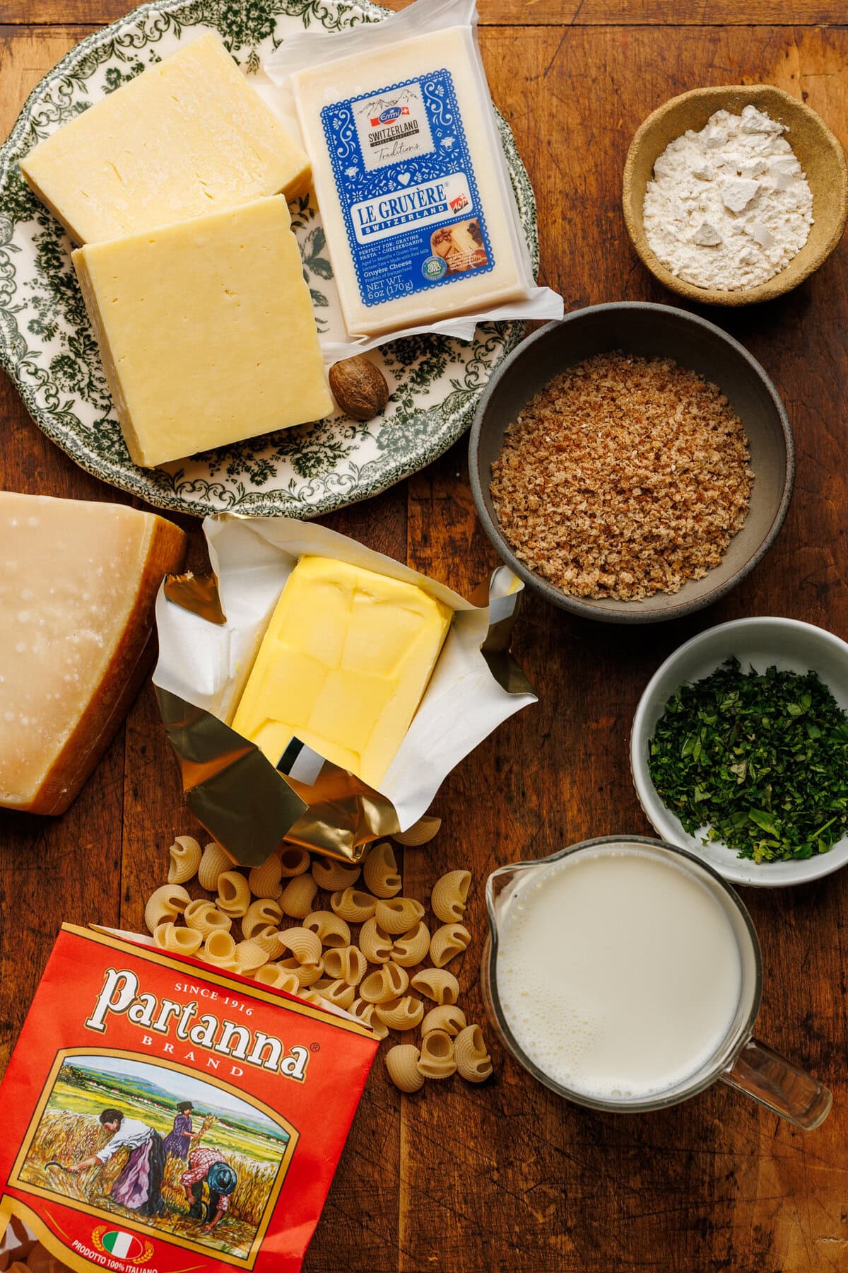 Ingredients for baked mac and cheese arranged on a wooden board.