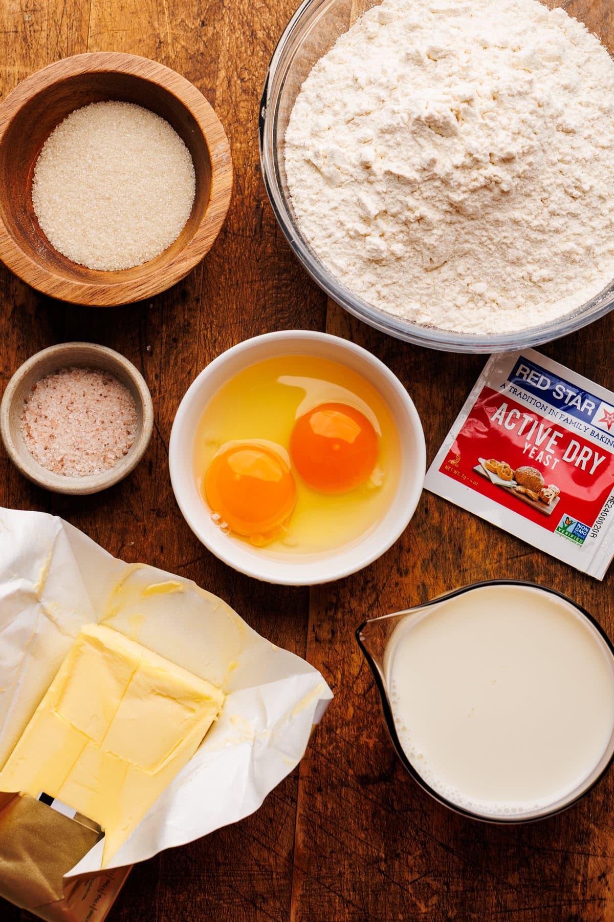 Ingredients for dinner rolls arranged on a wooden board.