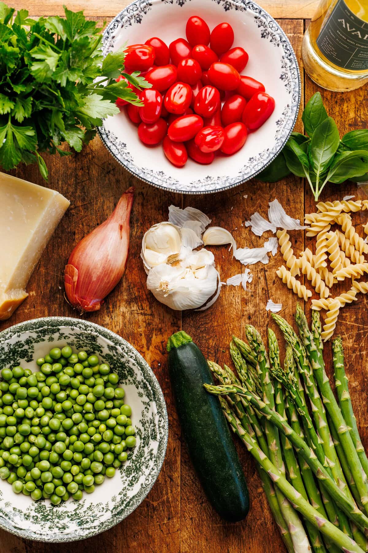 Ingredients for pasta primavera arranged on a brown wooden board. 
